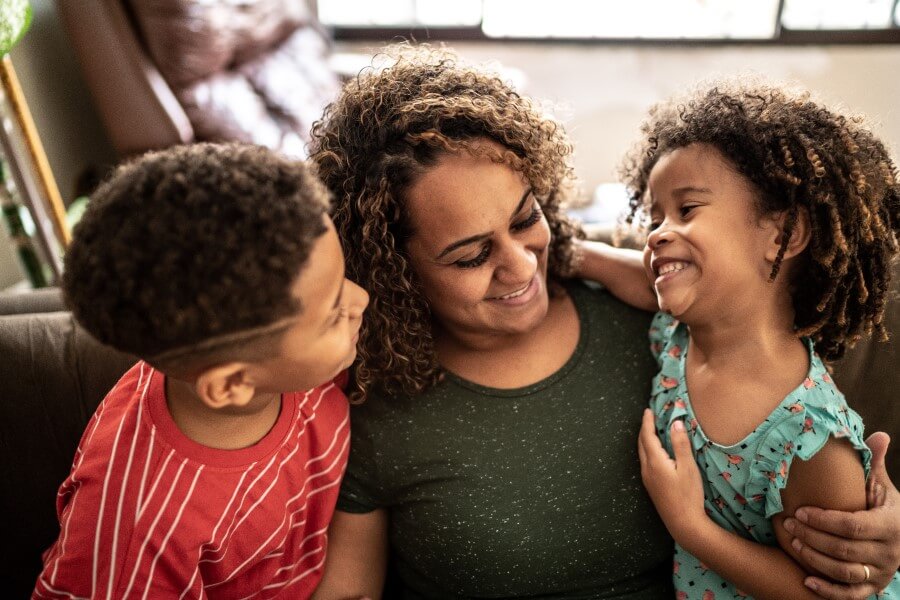Smiling parent sitting between two of her young children.
