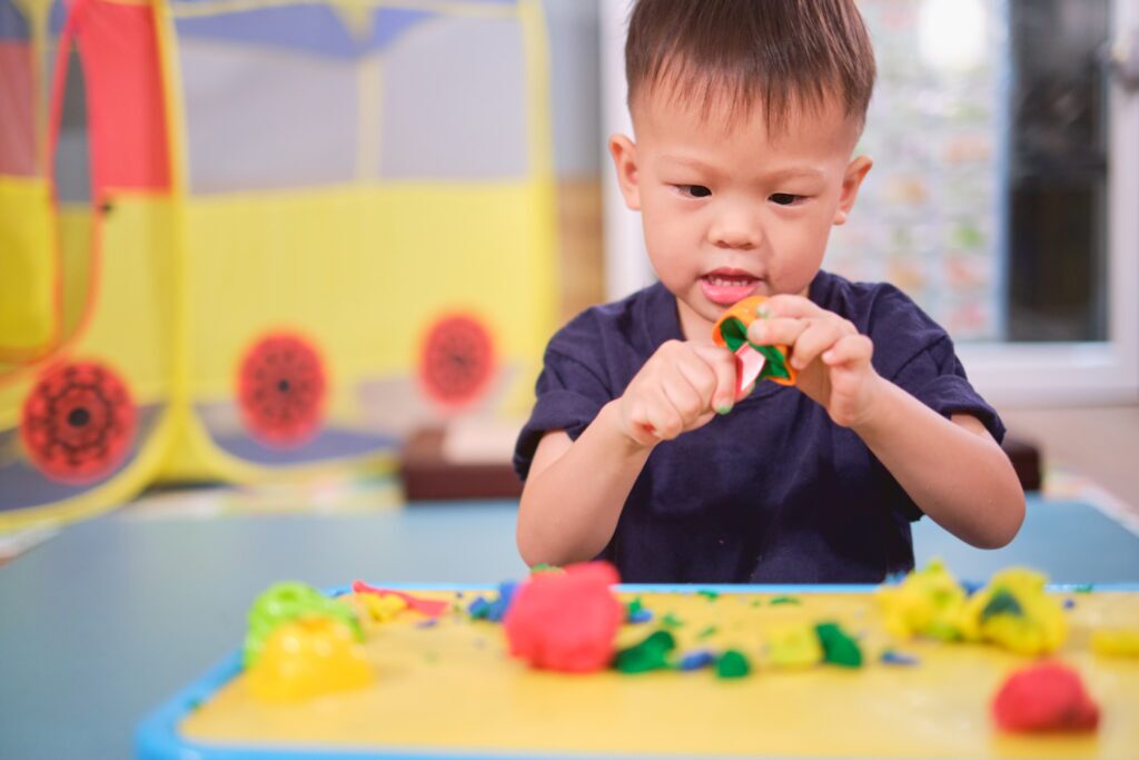 A toddler explores Play-Doh at day care. 
