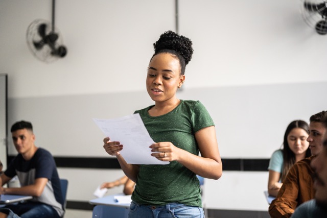 A black teenager reads out loud to her high school class.
