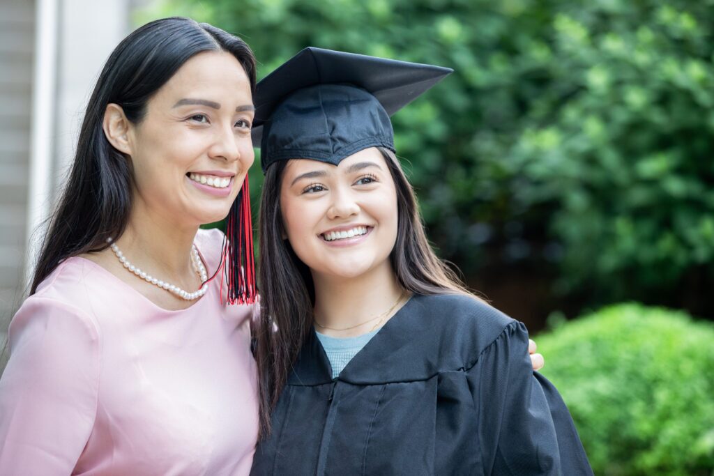Teenage girl and her mother smiling as she graduates high school