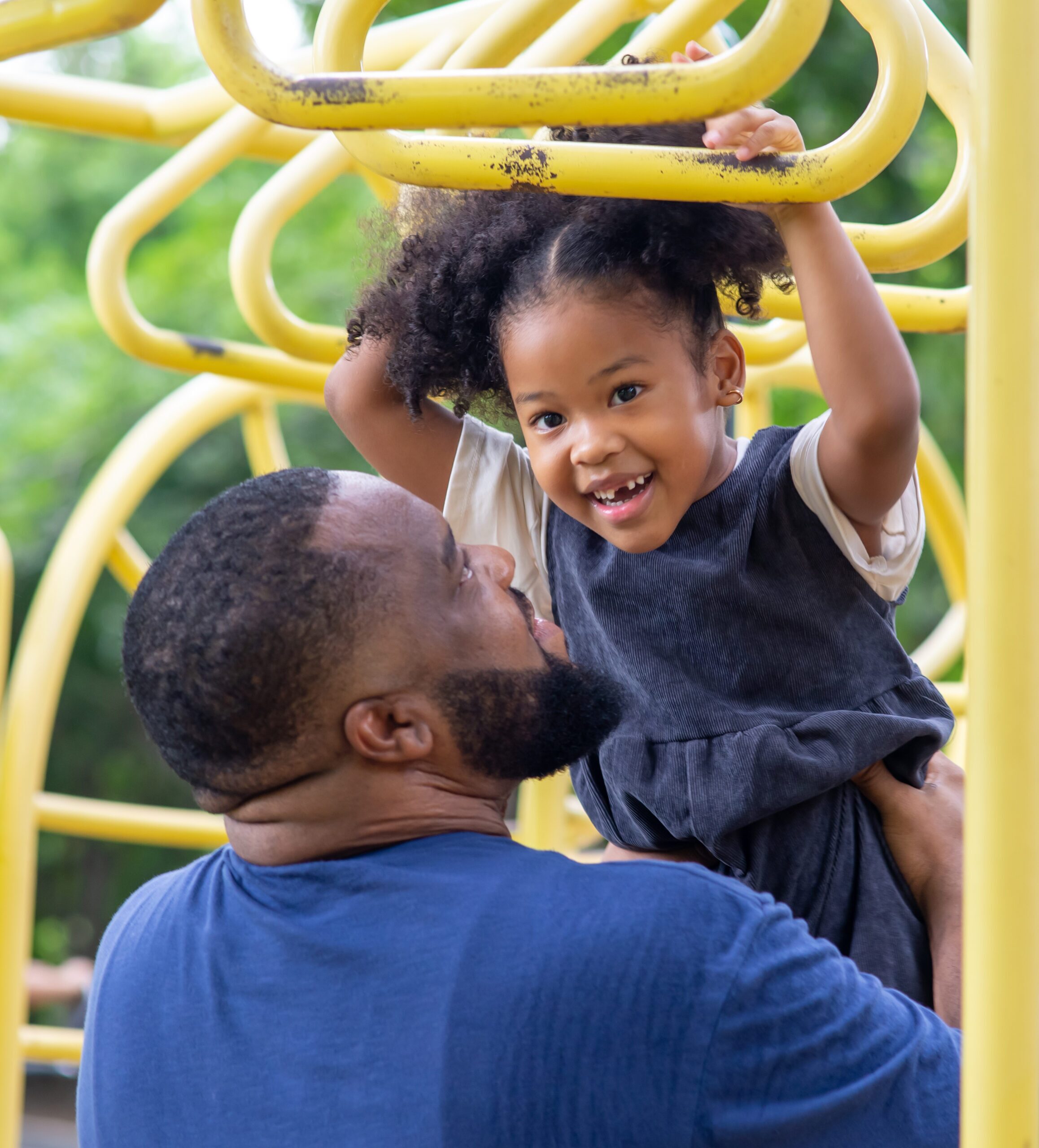 positive relationship between father and daughter An Asian father reads a book to his toddler daughter as they smile together.