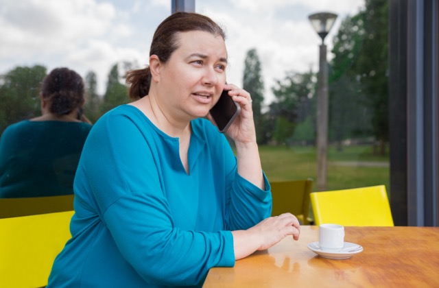Mature Caucasian woman speaking on mobile phone at a coffee shop.