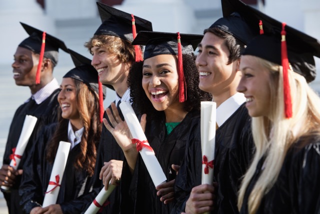 Multi-ethnic friends graduating highs school together, in cap and gown