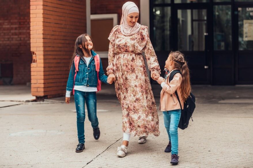Muslim mom and two daughters outside a school.