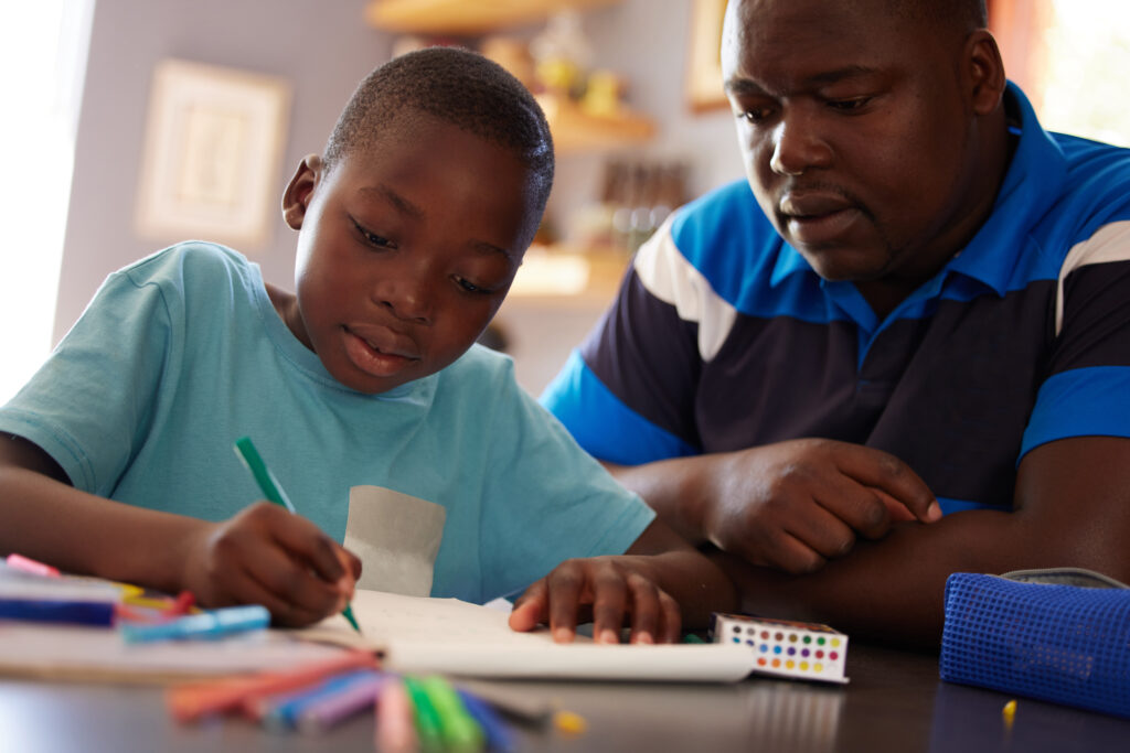 Focused father helps young son with finishing his homework.