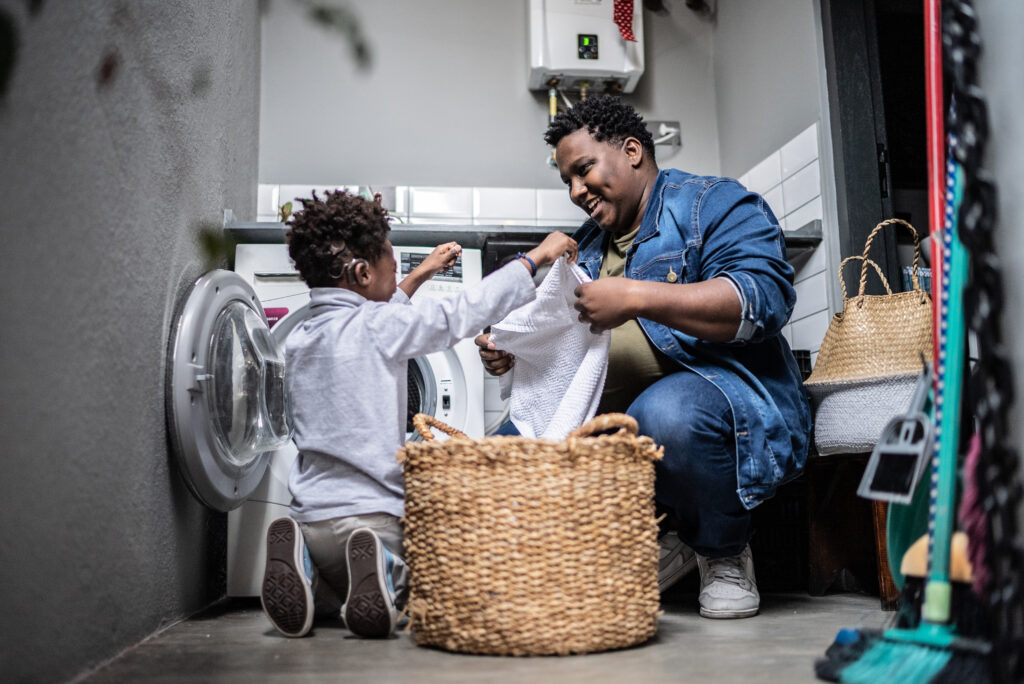 Black father and young son do laundry together.