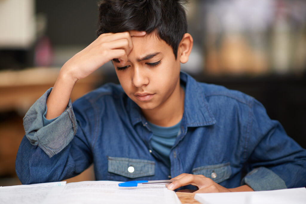 A middle school student concentrates as he works on a class assignment at his desk. 