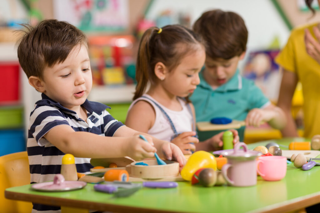 Preschool students play with clay and other materials in their classroom.