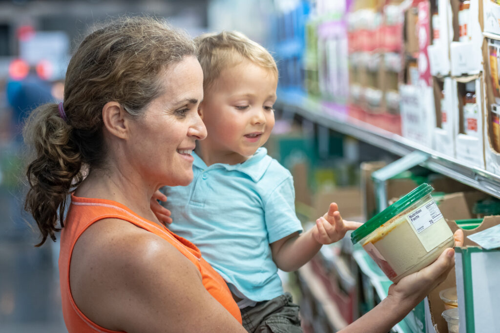 Smiling Caucasian Mature woman with her son shopping at the supermarket