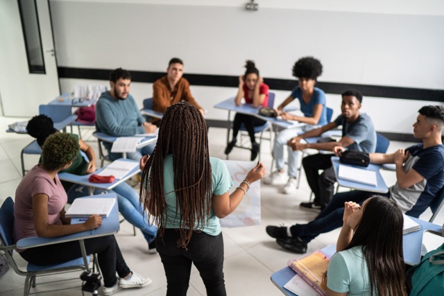A black teenager presents to her final project to the classroom.